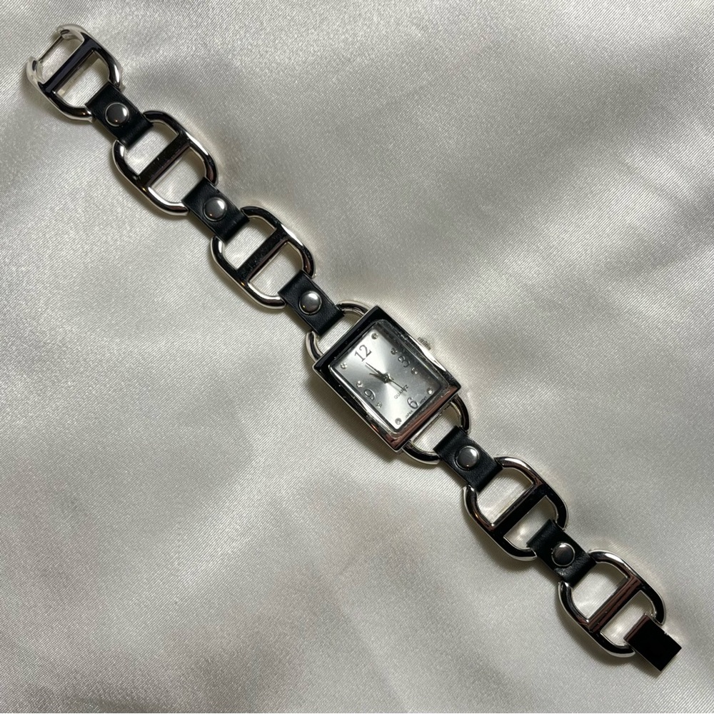 Silver tone buckle watch with black leather style grommets